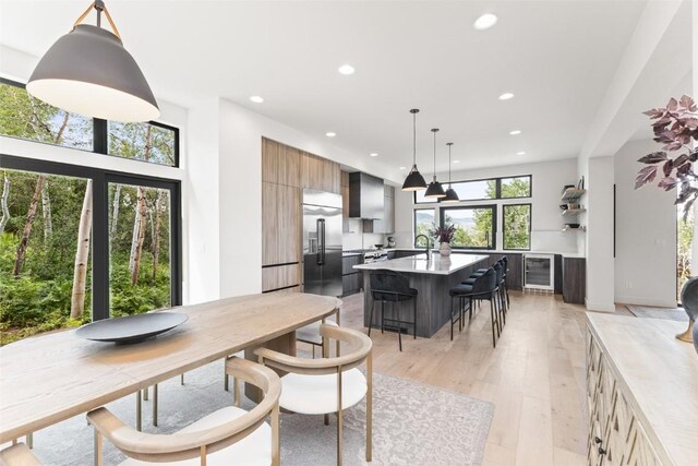 dining room featuring a wealth of natural light, light hardwood / wood-style flooring, and beverage cooler