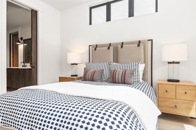 bedroom with ensuite bathroom and hardwood / wood-style flooring