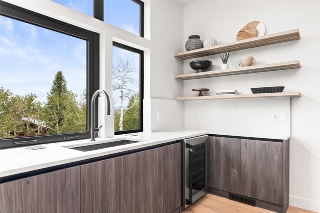 kitchen featuring dark brown cabinets, beverage cooler, plenty of natural light, and sink