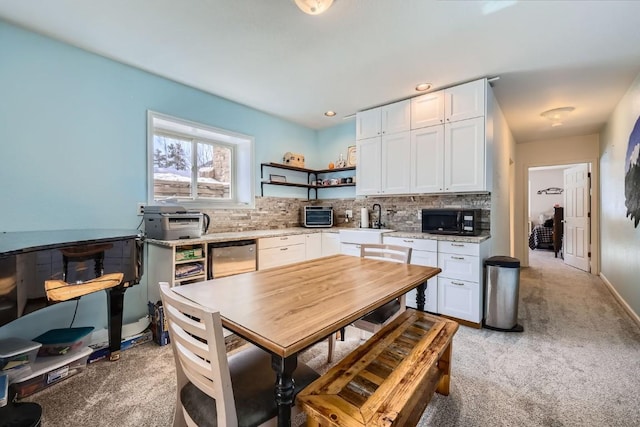 kitchen with tasteful backsplash, black microwave, light carpet, white cabinets, and open shelves