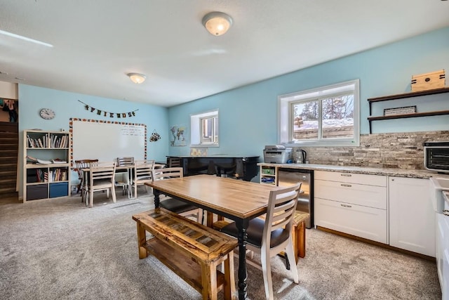 dining area with light colored carpet, a healthy amount of sunlight, and a toaster