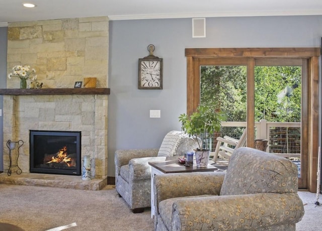 living room featuring a stone fireplace, crown molding, visible vents, and carpet floors