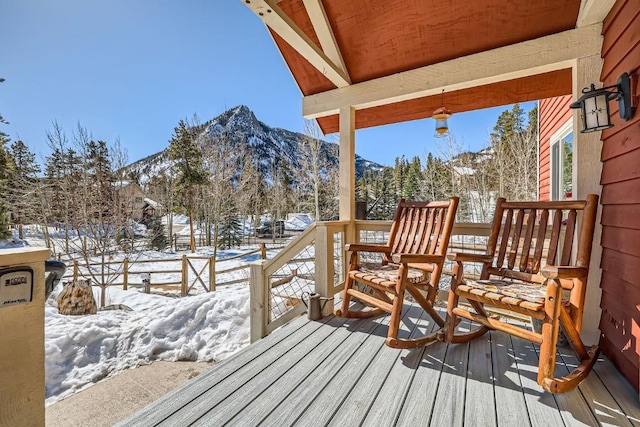 snow covered deck with a mountain view