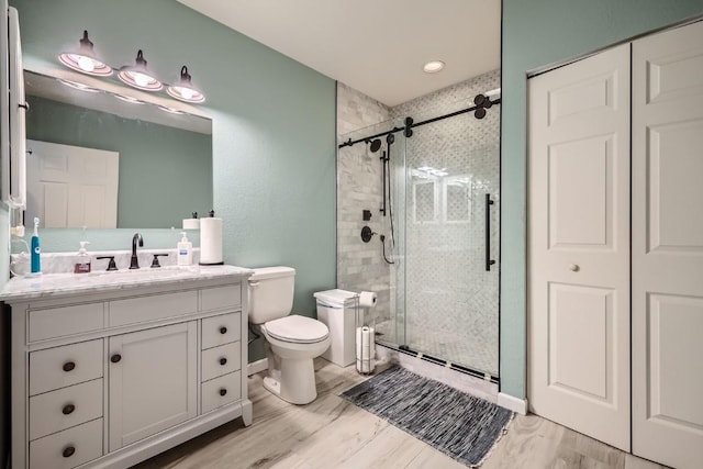 full bath with vanity, toilet, wood finished floors, and a stall shower