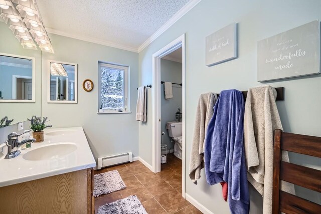 bathroom with a textured ceiling, crown molding, baseboard heating, and a sink