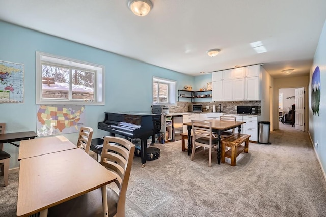 interior space with a sink, baseboards, and light colored carpet