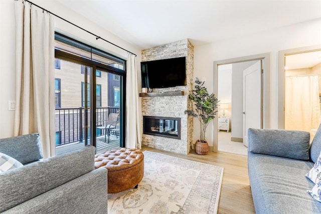 living room with a stone fireplace and light wood-type flooring