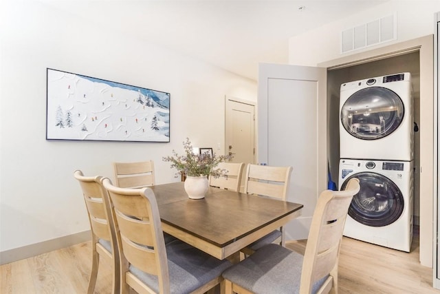 dining space with stacked washer / drying machine and light wood-type flooring