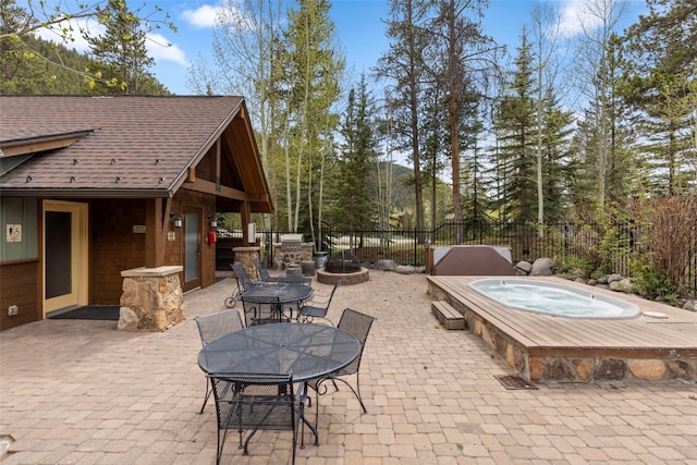 view of patio with an outdoor fire pit, fence, and an outdoor hot tub