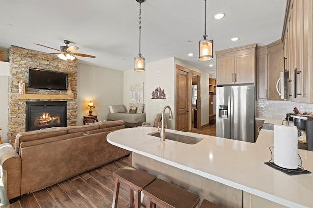 kitchen with a peninsula, dark wood-type flooring, a sink, light countertops, and appliances with stainless steel finishes