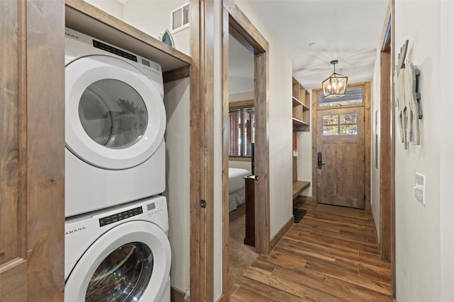 washroom with laundry area, visible vents, stacked washer / dryer, wood finished floors, and a chandelier