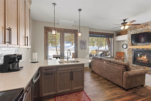 kitchen featuring open floor plan, dark wood-type flooring, a peninsula, light countertops, and a sink