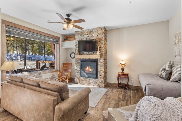 living room with a fireplace, wood finished floors, a ceiling fan, and baseboards