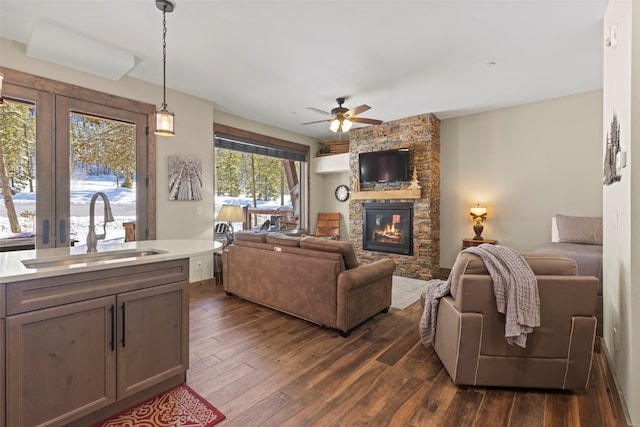 living area with dark wood-style floors, a fireplace, and a ceiling fan