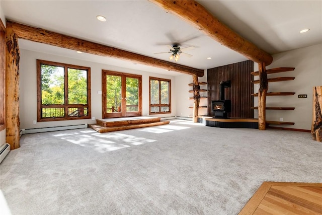 unfurnished living room with a wood stove, carpet flooring, ceiling fan, a baseboard radiator, and beamed ceiling