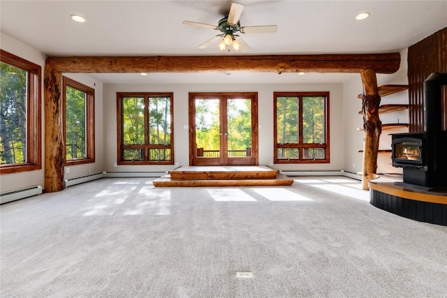 unfurnished living room with beam ceiling, a wood stove, light carpet, and ceiling fan