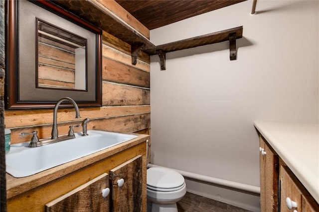 bathroom with vanity, wood walls, and toilet