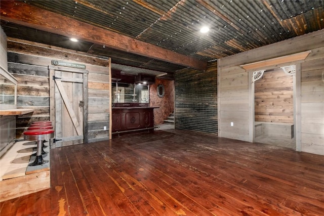 bar featuring hardwood / wood-style floors, a barn door, and wooden walls