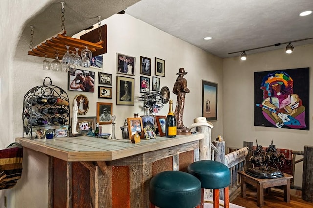 bar featuring tile countertops, hardwood / wood-style floors, and track lighting