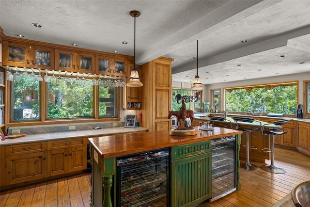 kitchen with pendant lighting, a center island, light hardwood / wood-style floors, and beverage cooler