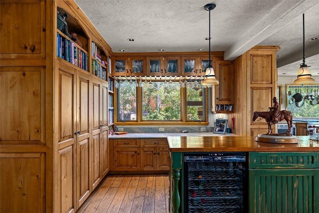 kitchen featuring pendant lighting, light wood-type flooring, a textured ceiling, and wine cooler