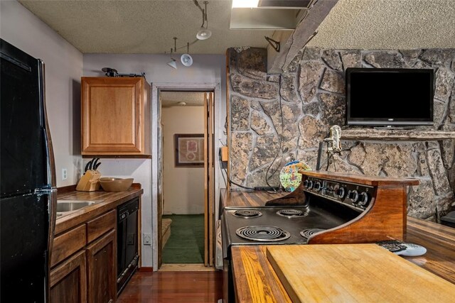 kitchen with a textured ceiling, butcher block countertops, dark wood-type flooring, and black appliances