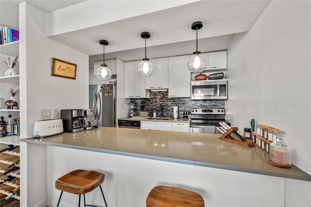 kitchen with pendant lighting, sink, appliances with stainless steel finishes, white cabinetry, and kitchen peninsula