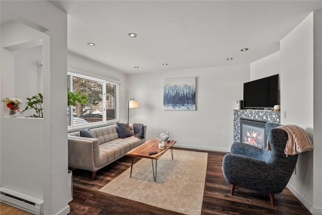 living room featuring baseboard heating, a fireplace, and dark wood-type flooring