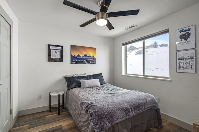 bedroom with dark wood-style floors, baseboards, visible vents, and ceiling fan