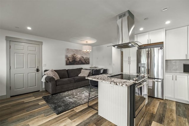 kitchen with appliances with stainless steel finishes, light stone counters, island exhaust hood, a kitchen bar, and white cabinetry