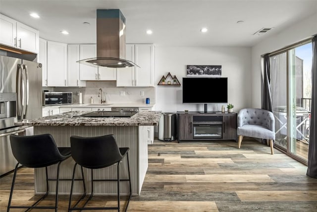 kitchen featuring visible vents, light wood-style flooring, stainless steel appliances, white cabinetry, and island range hood