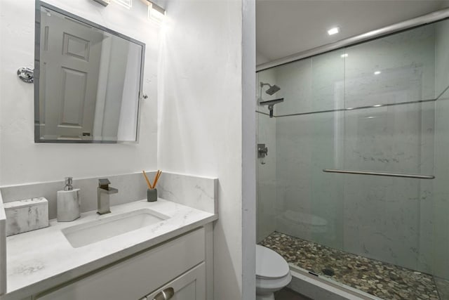 bathroom with a stall shower, vanity, and toilet