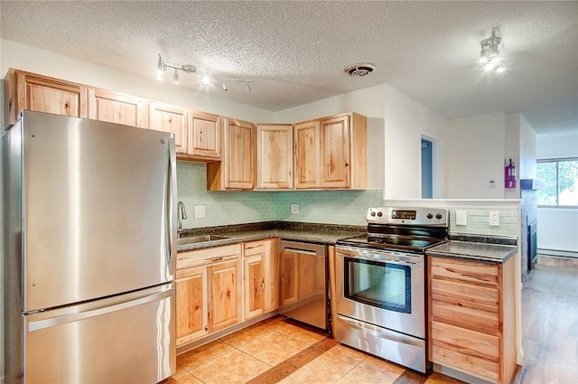 kitchen with appliances with stainless steel finishes, backsplash, sink, light tile patterned floors, and light brown cabinets