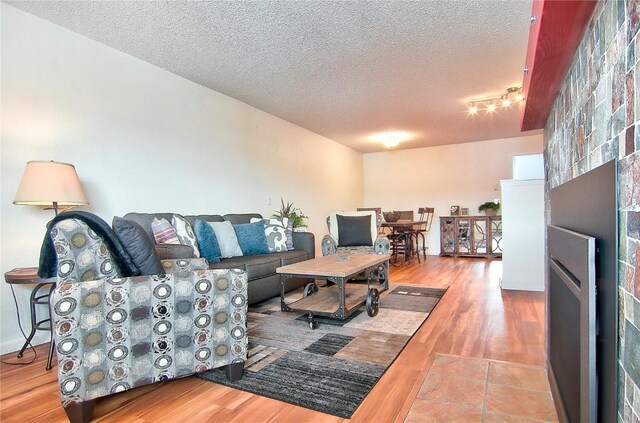 unfurnished bedroom featuring a textured ceiling, baseboard heating, multiple windows, dark hardwood / wood-style flooring, and a closet