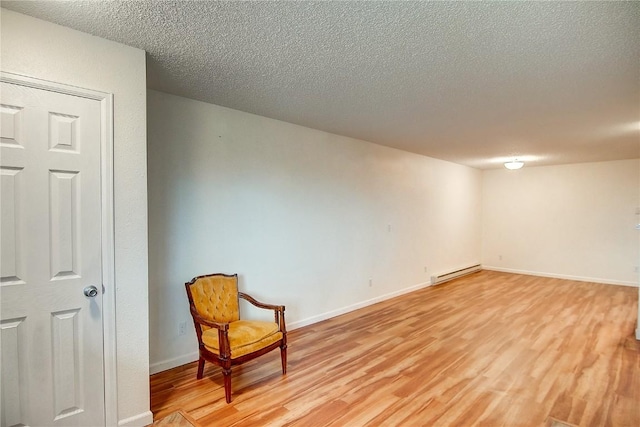 sitting room featuring a baseboard radiator, a textured ceiling, and light wood-type flooring