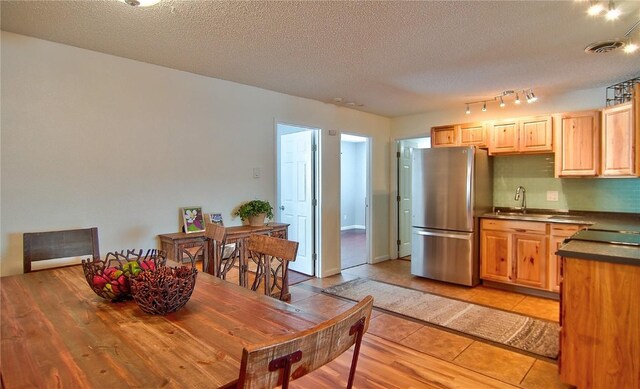 living room featuring a textured ceiling, a fireplace, light hardwood / wood-style floors, and baseboard heating