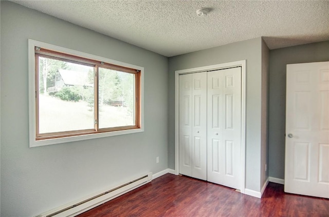 unfurnished bedroom featuring dark wood-type flooring, a closet, a baseboard radiator, and a textured ceiling