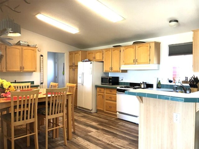 kitchen with tile counters, sink, dark hardwood / wood-style floors, lofted ceiling, and white appliances