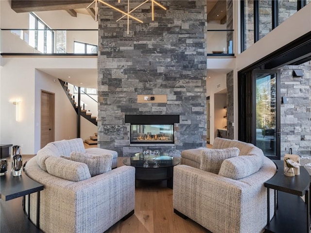 living room featuring a fireplace, wood-type flooring, and a towering ceiling