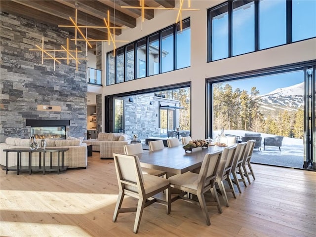 dining space featuring a fireplace, wood-type flooring, beamed ceiling, a mountain view, and a high ceiling