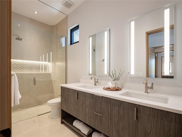 bathroom featuring tile patterned flooring, vanity, toilet, and a shower with door