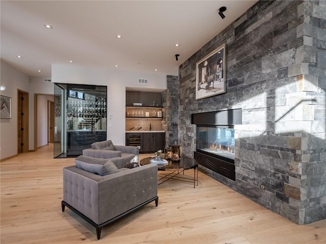 living room featuring a fireplace, indoor bar, and light wood-type flooring