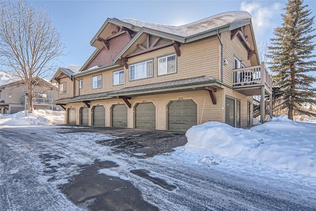 snow covered property with a balcony and a garage