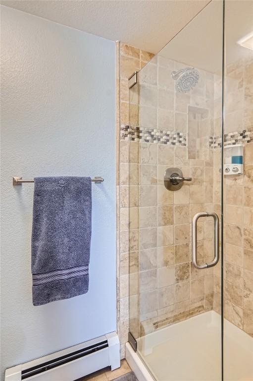 bathroom with a shower with door and baseboard heating