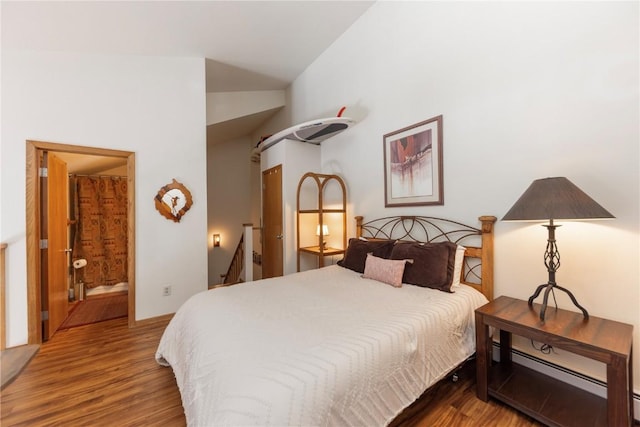 bedroom featuring a baseboard heating unit, wood finished floors, connected bathroom, and lofted ceiling