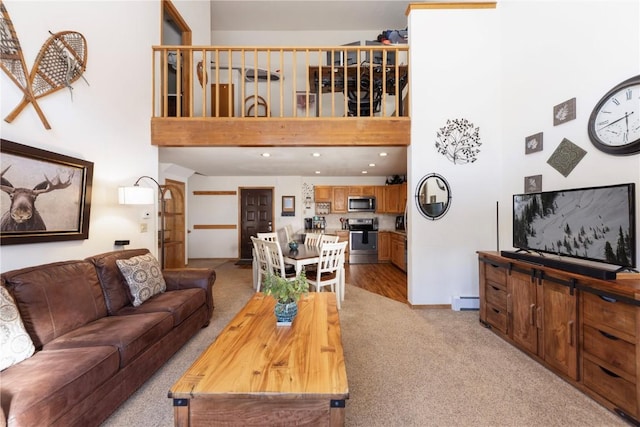 living room with a baseboard radiator, light colored carpet, a towering ceiling, and baseboards