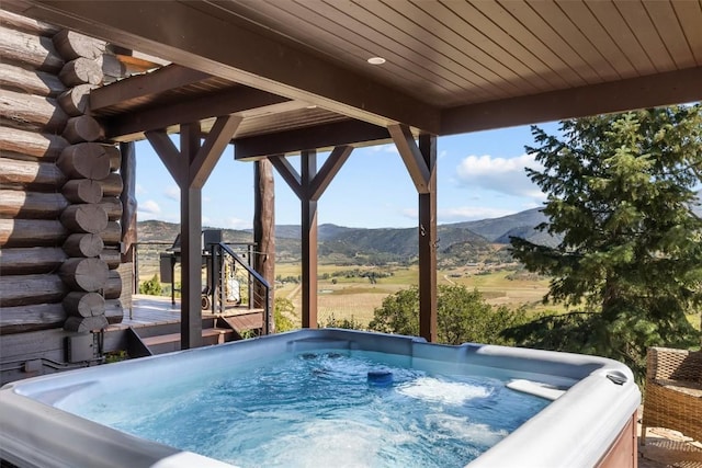 view of swimming pool with a mountain view, a rural view, and a hot tub