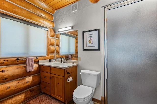 bathroom with toilet, vanity, rustic walls, and a shower with shower door