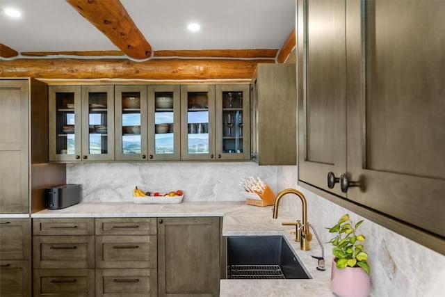 kitchen with light stone countertops, beam ceiling, and sink