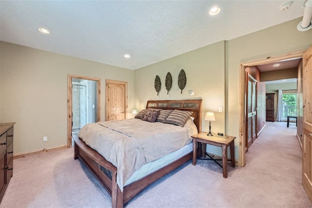 bedroom featuring ensuite bathroom and light carpet